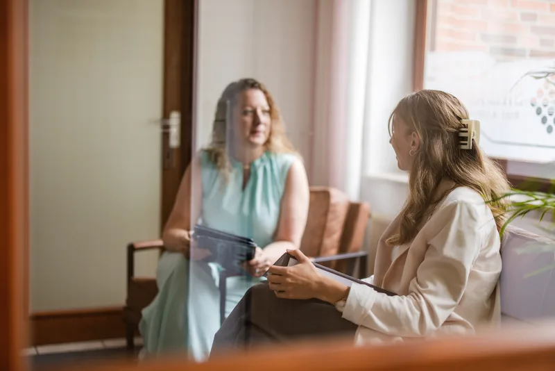 Persönliche Beratung in entspannter Atmosphäre – Steuerberater RKK in Rhauderfehn Zwei Frauen schauen gemeinsam auf ein Tablet in einem freundlichen Wartebereich der Kanzlei RKK