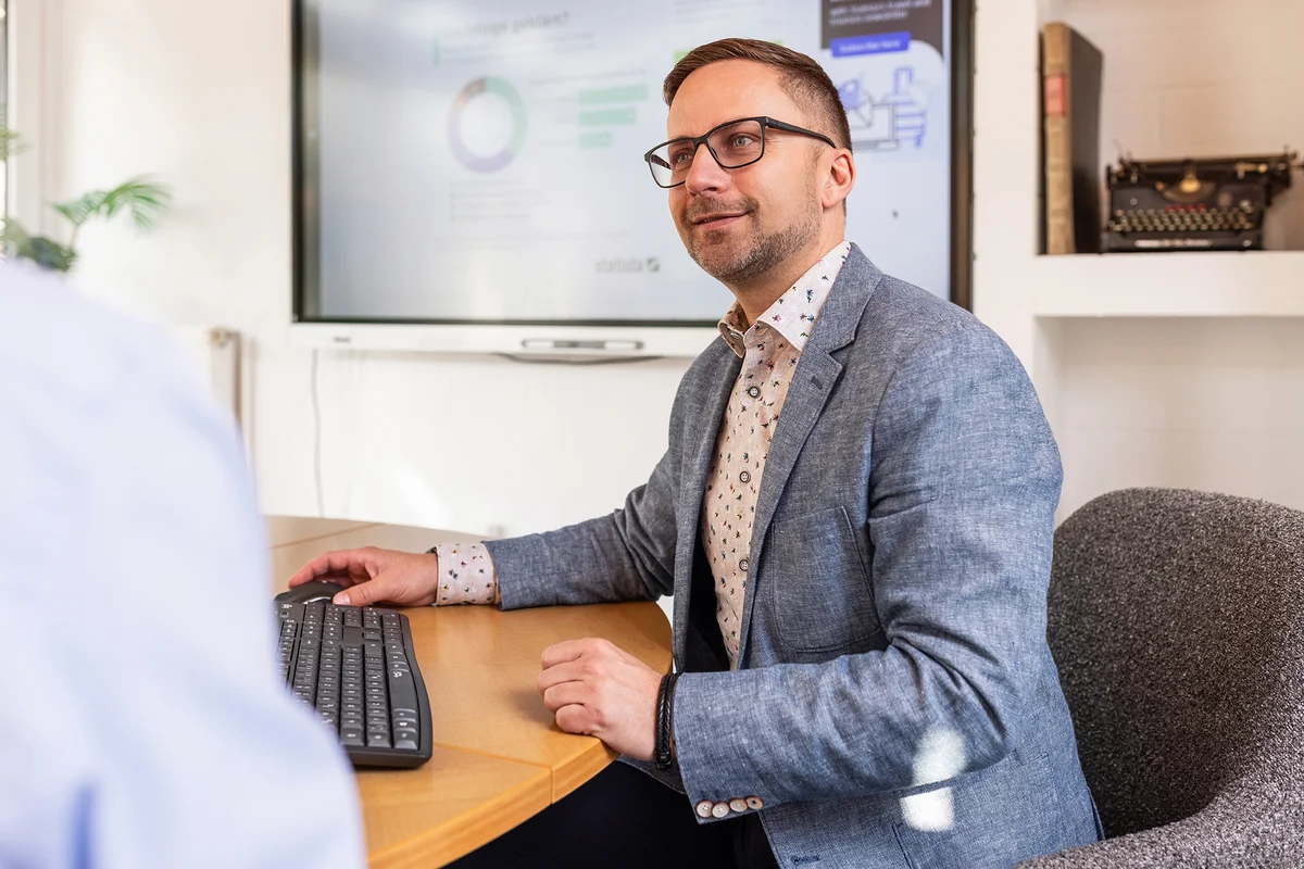 Digitale Steuerberatung bei RKK – Moderne Steuerlösungen für Unternehmen in Rhauderfehn Steuerberater Fabian Kaukereit sitzt am Computer mit Statistikdiagramm auf dem Bildschirm und berät einen Mandanten