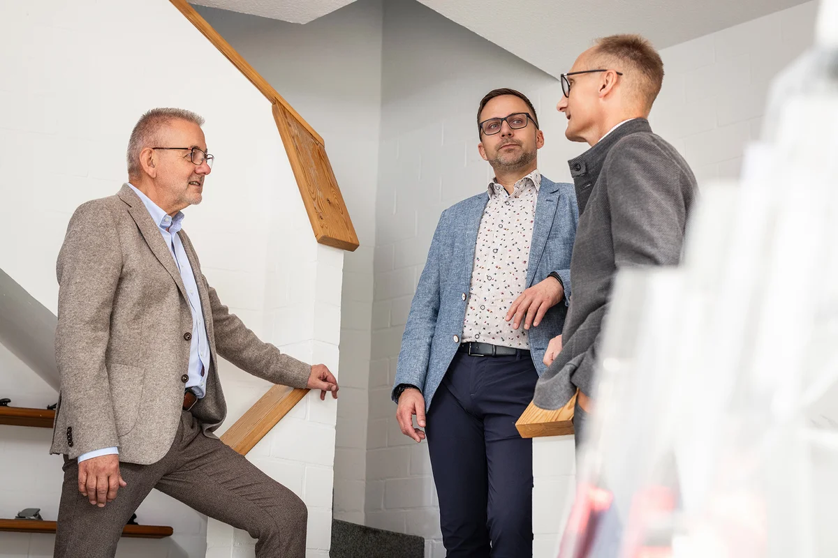 Das Partnerteam bei RKK – Rüst, Kämpfert und Kaukereit im kollegialen Austausch Die drei Partner der Steuerberatungskanzlei RKK stehen im Treppenhaus und sprechen miteinander
