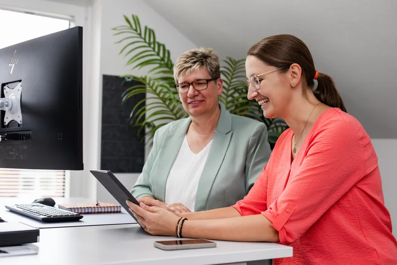 Digitales Teamwork bei Steuerberater RKK – Modernes Arbeiten für beste Beratungsergebnisse Zwei Mitarbeiterinnen der Kanzlei RKK schauen gemeinsam auf ein Tablet am Schreibtisch
